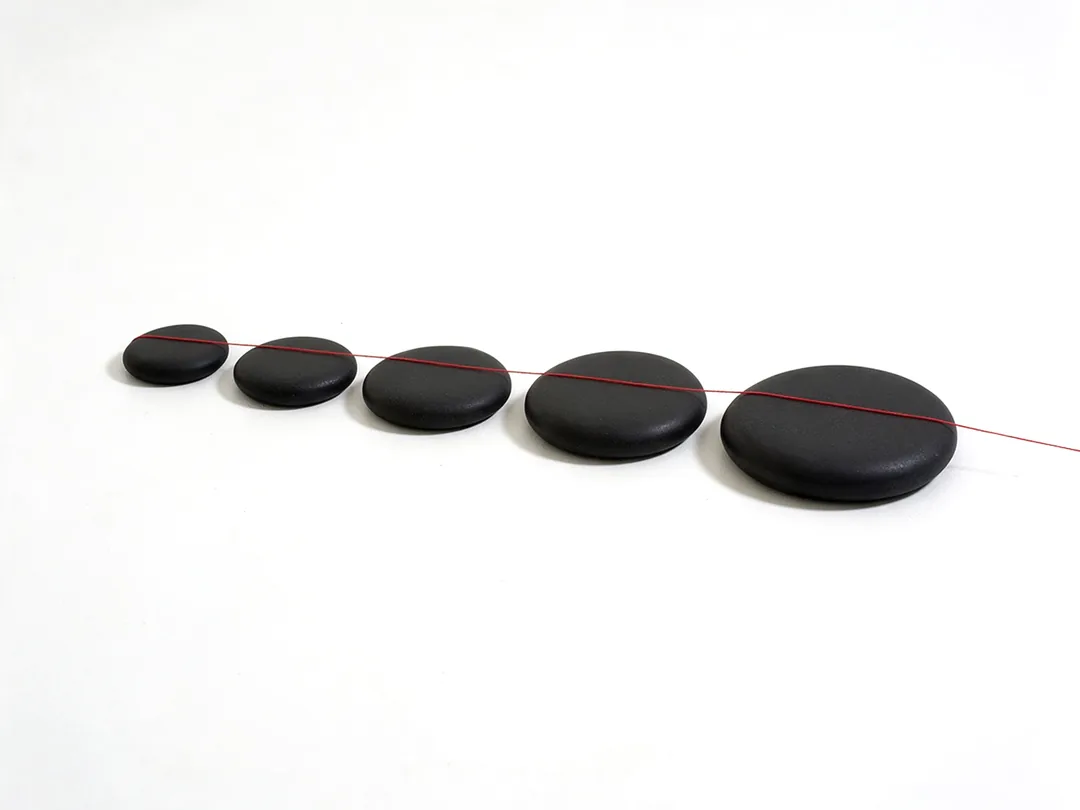 Camino de piedras negras recorrido por un hilo rojo