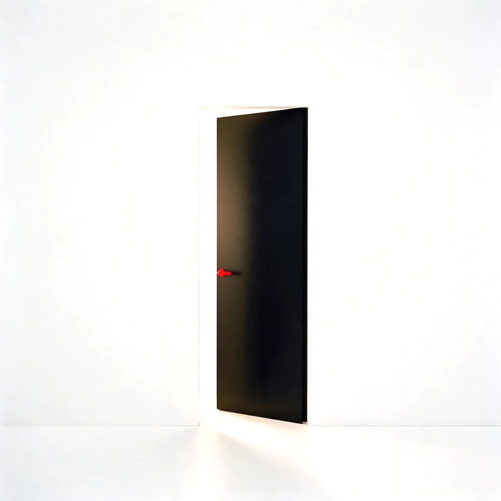 Puerta negra entreabierta con un tirador rojo
